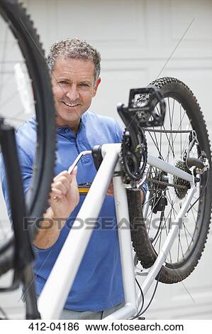 Stock Photograph - Man working on bicycle in driveway. Fotosearch