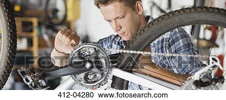 Man working on bicycle in shop View Large Photo Image Stock Image - Man working on bicycle in shop. Fotosearch