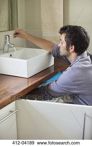 Plumber working on bathroom sink View Large Photo Image Stock Photo - Plumber working on bathroom sink. Fotosearch