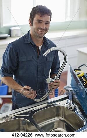 Stock Photograph - Plumber working on kitchen sink. Fotosearch