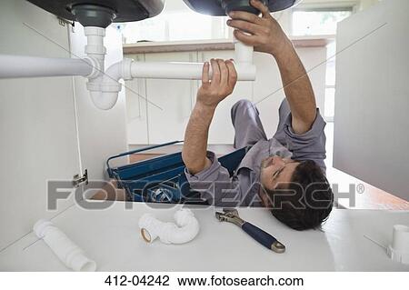Plumber working on pipes under kitchen sink View Large Photo Image Stock Image - Plumber working on pipes under kitchen sink. Fotosearch