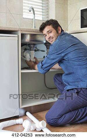 Plumber working on pipes under kitchen sink View Large Photo Image Stock Image - Plumber working on pipes under kitchen sink. Fotosearch