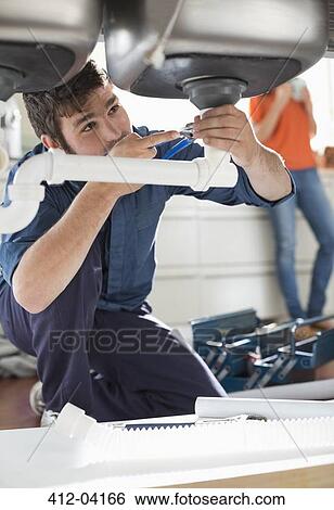 Plumber working on pipes under sink View Large Photo Image Stock Photograph - Plumber working on pipes under sink. Fotosearch