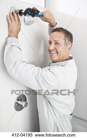 Plumber working on shower head in bathroom View Large Photo Image Stock Image - Plumber working on shower head in bathroom. Fotosearch