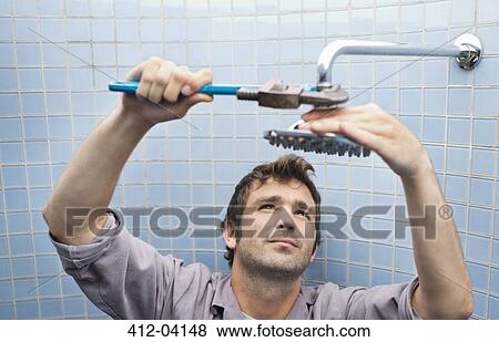 Plumber working on shower head in bathroom View Large Photo Image Stock Photo - Plumber working on shower head in bathroom. Fotosearch