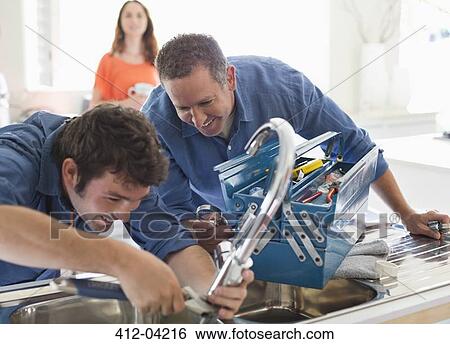 Plumbers working on kitchen sink View Large Photo Image Stock Photograph - Plumbers working on kitchen sink. Fotosearch