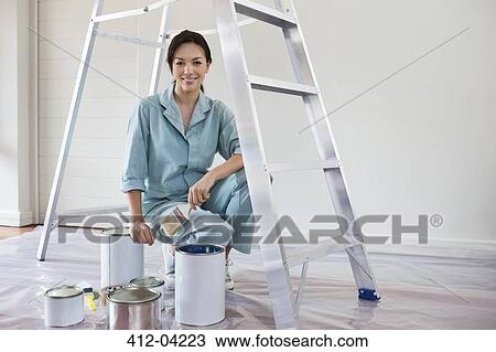 Stock Image - Smiling woman painting room. Fotosearch