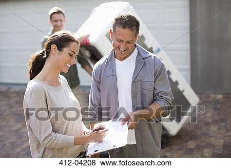 Woman signing for delivery in driveway View Large Photo Image Stock Photo - Woman signing for delivery in driveway. Fotosearch