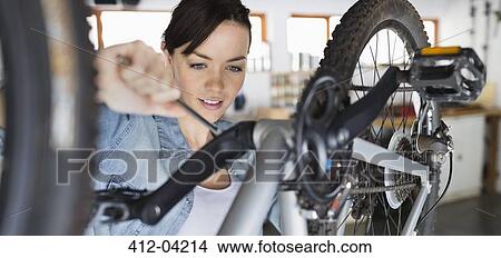 Woman working on bicycle in shop View Large Photo Image Picture - Woman working on bicycle in shop. Fotosearch