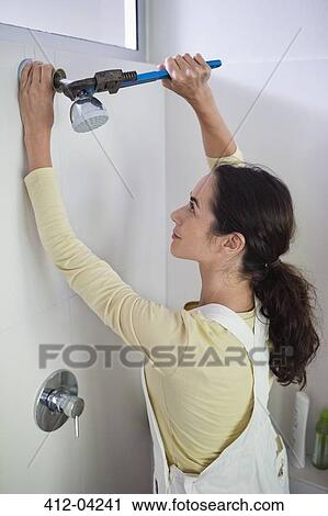 Woman working on shower head in bathroom View Large Photo Image Stock Image - Woman working on shower head in bathroom. Fotosearch