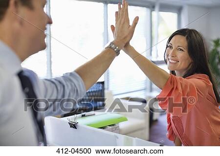 Stock Image - Business people high fiving in office. Fotosearch