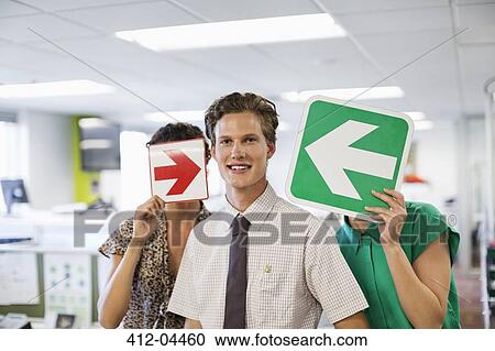 Stock Image - Business people holding arrows in office. Fotosearch