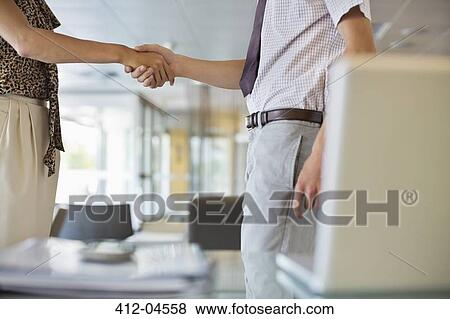 Stock Photo - Business people shaking hands in office. Fotosearch