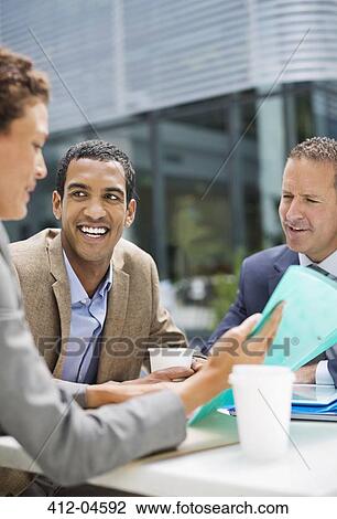 Stock Image - Business people talking in meeting outdoors. Fotosearch
