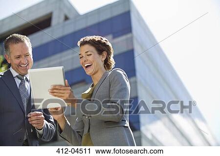 Stock Image - Business people using tablet computer outdoors. Fotosearch