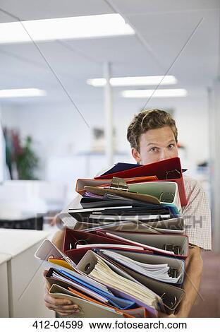 Businessman balancing folders in office View Large Photo Image Stock Photo - Businessman balancing folders in office. Fotosearch