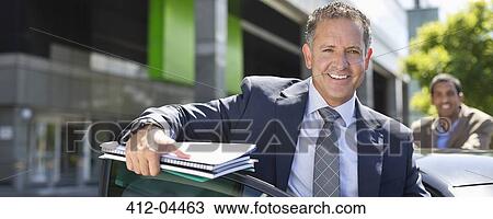 Businessman climbing out of car View Large Photo Image Stock Image - Businessman climbing out of car. Fotosearch