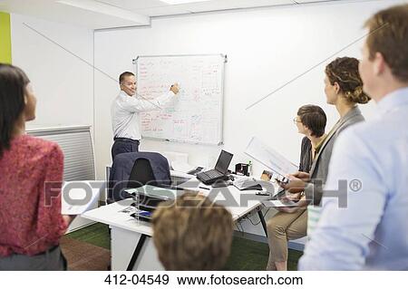 Stock Photo - Businessman drawing on whiteboard in meeting. Fotosearch