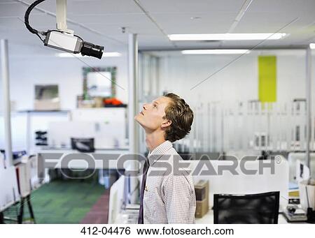 Stock Photograph - Businessman examining security camera in office. Fotosearch