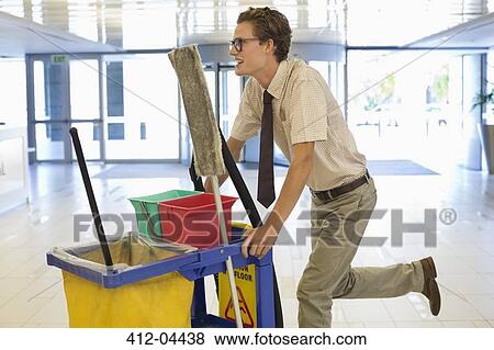 Businessman pushing cleaning cart in office View Large Photo Image Stock Photo - Businessman pushing cleaning cart in office. Fotosearch