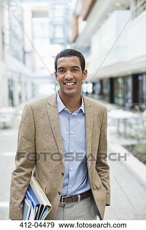 Businessman smiling on city street View Large Photo Image Stock Photo - Businessman smiling on city street. Fotosearch
