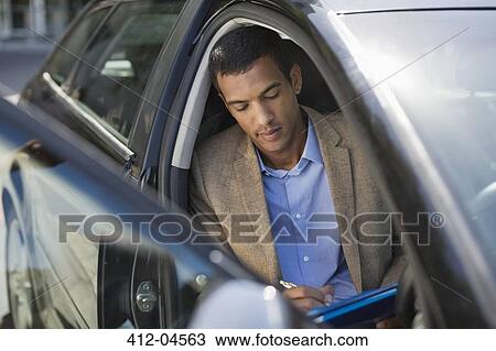 Stock Image - Businessman working in car. Fotosearch