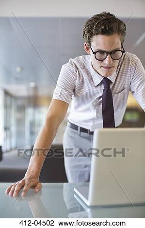 Stock Image - Businessman working on laptop at desk. Fotosearch