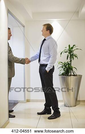 Stock Image - Businessmen shaking hands in office. Fotosearch