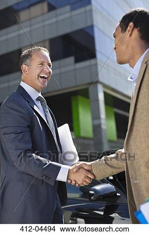 Picture - Businessmen shaking hands outdoors. Fotosearch