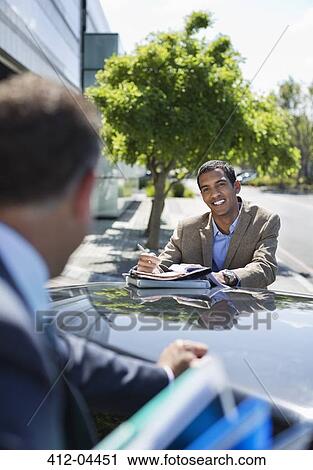 Stock Image - Businessmen talking at car. Fotosearch