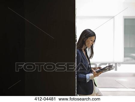 Stock Image - Businesswoman reading in office. Fotosearch