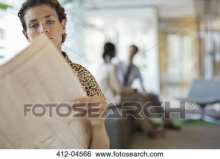 Stock Photograph - Businesswoman reading newspaper in office. Fotosearch
