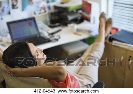 Stock Image - Businesswoman relaxing at desk. Fotosearch