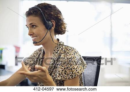 Businesswoman talking on headset at desk View Large Photo Image Stock Photo - Businesswoman talking on headset at desk. Fotosearch
