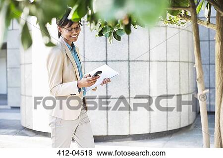 Stock Photo - Businesswoman using cell phone outdoors. Fotosearch