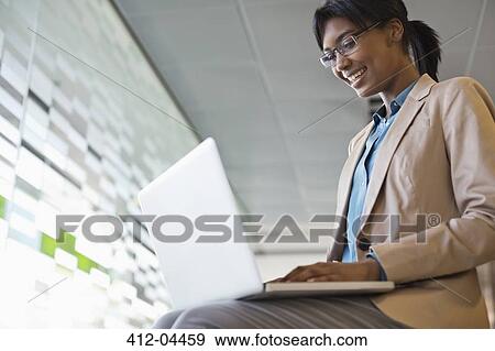 Businesswoman using laptop in office View Large Photo Image Stock Photo - Businesswoman using laptop in office. Fotosearch