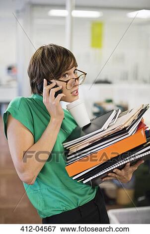 Businesswoman with folders talking on cell phone View Large Photo Image Stock Photo - Businesswoman with folders talking on cell phone. Fotosearch