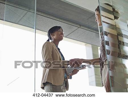 Stock Photo - Businesswomen shaking hands in office. Fotosearch