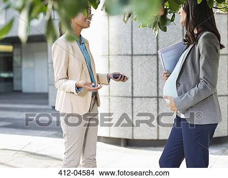Picture - Businesswomen talking on city street. Fotosearch