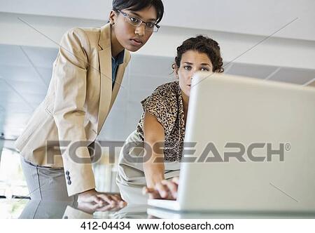 Businesswomen using laptop together View Large Photo Image Picture - Businesswomen using laptop together. Fotosearch