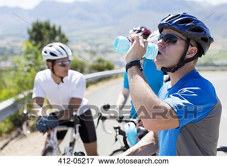 Stock Photo - Cyclist drinking water on rural road. Fotosearch