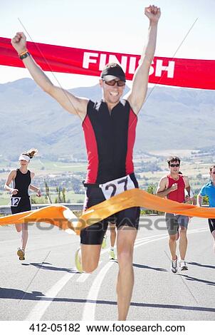 Stock Image - Runner crossing race finish line. Fotosearch