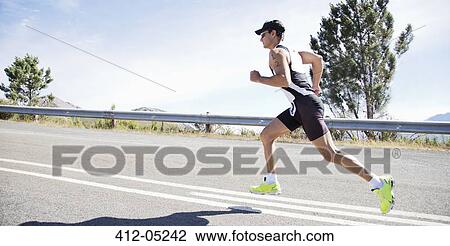 Stock Image - Runner in race on rural road. Fotosearch