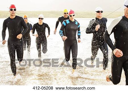 Swimmers in wetsuits walking in waves View Large Photo Image Stock Photo - Swimmers in wetsuits walking in waves. Fotosearch