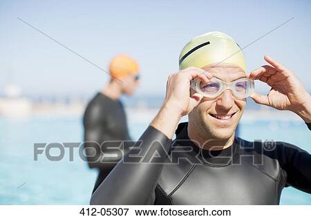 Stock Photo - Triathlete adjusting goggles outdoors. Fotosearch