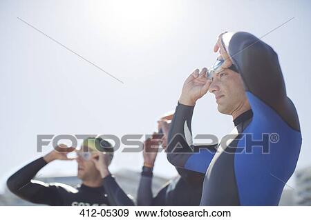 Stock Photo - Triathletes adjusting goggles outdoors. Fotosearch