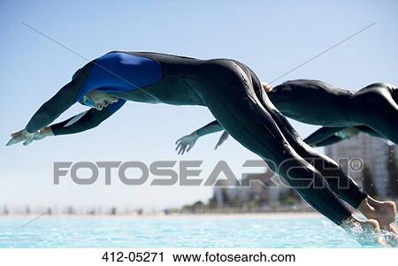 Stock Image - Triathletes diving into swimming pool. Fotosearch