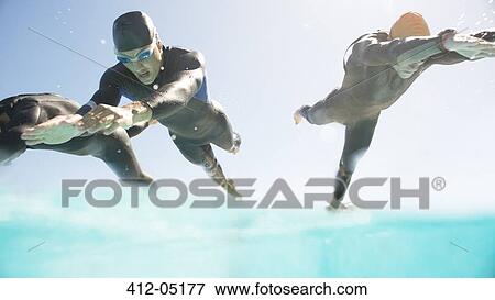 Triathletes in wetsuits running into ocean View Large Photo Image Stock Photo - Triathletes in wetsuits running into ocean. Fotosearch