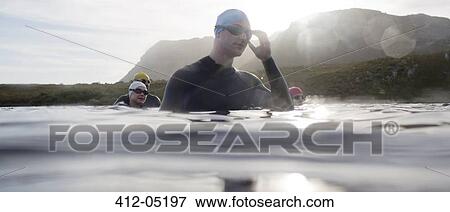 Triathletes in wetsuits standing in water View Large Photo Image Stock Photo - Triathletes in wetsuits standing in water. Fotosearch