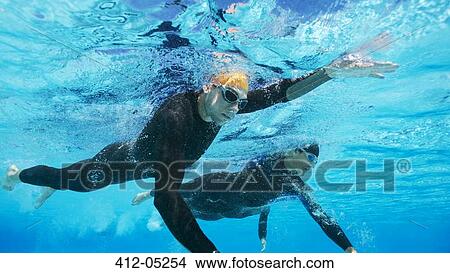 Picture - Triathletes in wetsuits underwater. Fotosearch